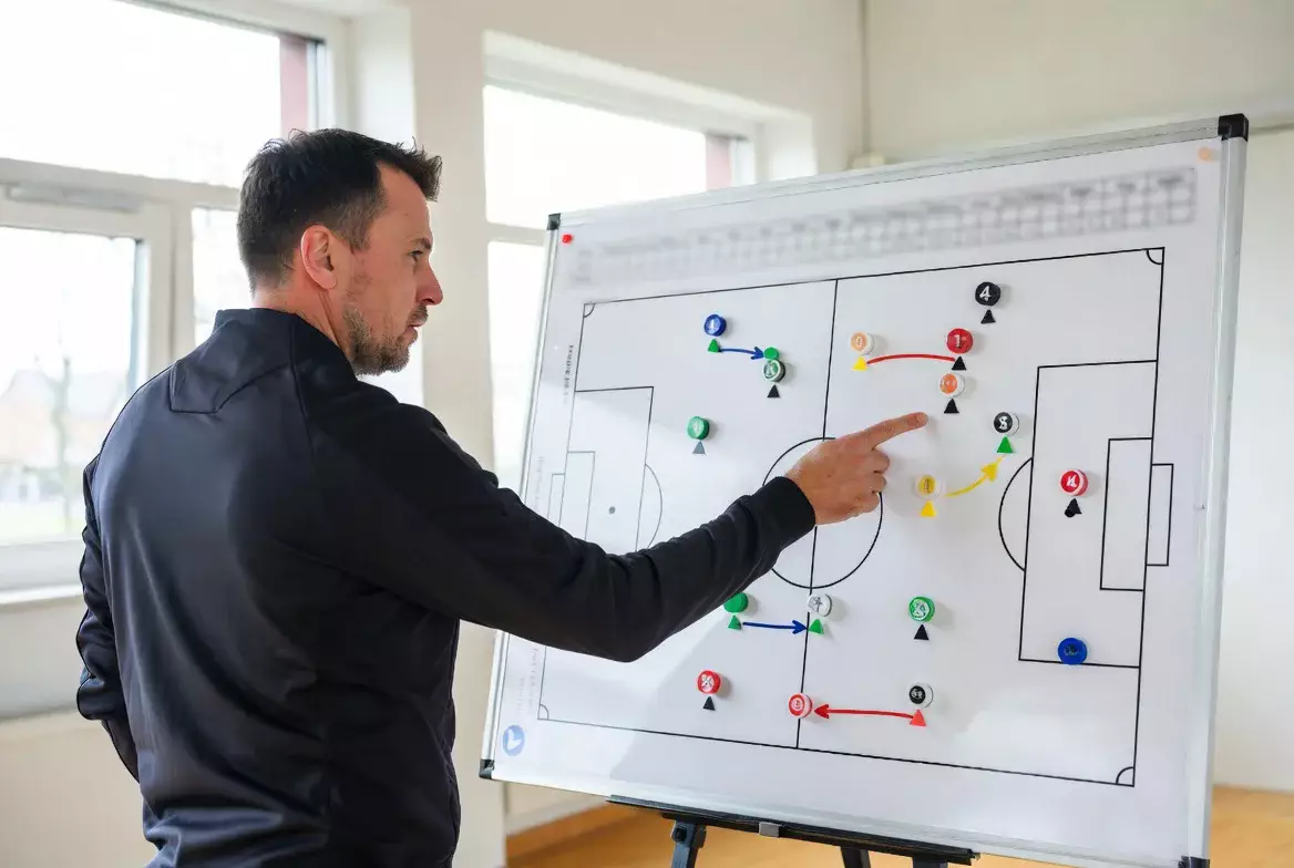 Trainer analysiert Spielzüge an einer Taktiktafel mit statistischen Notizen